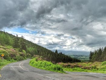 Scenic view of road by mountains against sky