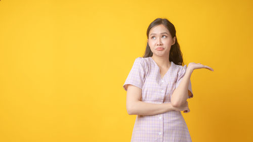 Portrait of a beautiful young woman against yellow background