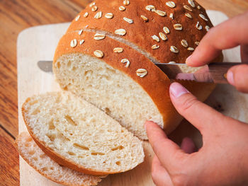 Woman use knife to slicing homemade bread bakery on wooden cutting board.