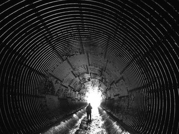 Rear view of a woman walking in e drainage tunnel