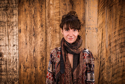 Portrait of smiling young woman standing against wall