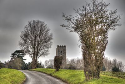 Road amidst trees on field against sky