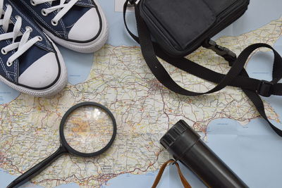 Close-up of magnifying glass with shoes and flashlight on map