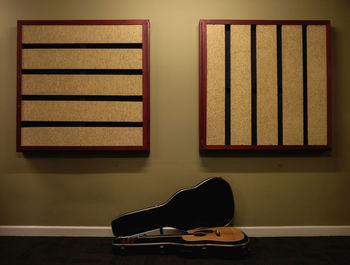 Acoustic guitar on floor against wall