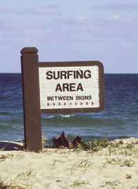 Information sign on beach against sky