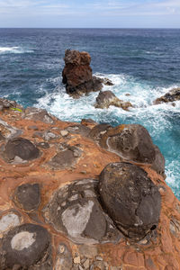 Rock formation on beach against sky