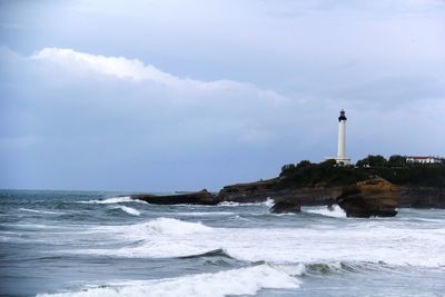 Lighthouse by sea against sky