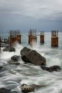 Pier on sea against cloudy sky
