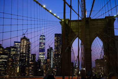 Brooklyn bridge against illuminated buildings in city against sky at dusk