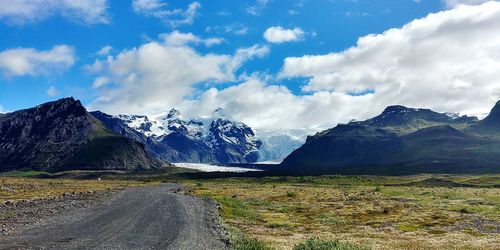 Road by mountains against sky