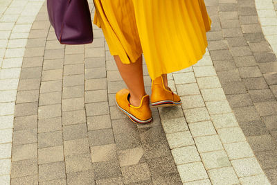 Low section of mature women walking on pavement