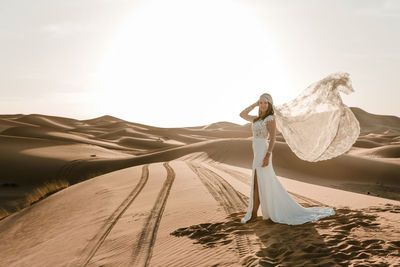 Woman with umbrella on sand dune in desert