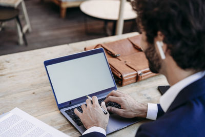 Businessman typing on laptop sitting at table in cafe