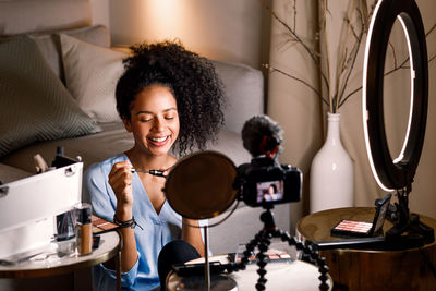 Young influencer vlogging while applying make-up at home