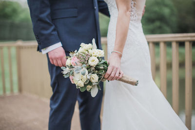 Midsection of newlywed couple standing outdoors