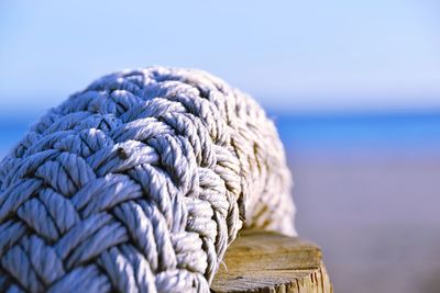 Close-up of rope on wooden post against sky