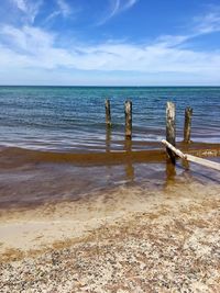 Wooden posts on beach against sky