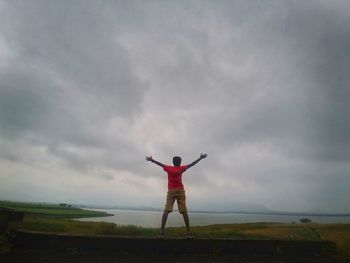 Rear view of man with arms outstretched standing on land