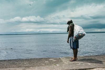 Full length of man standing at sea shore against sky