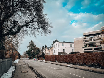 Road by buildings in city against sky