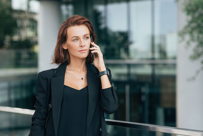 Young woman looking away while standing outdoors