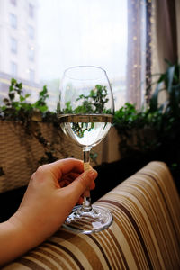 Close-up of hand holding glass of wine in dark atmospheric bar 