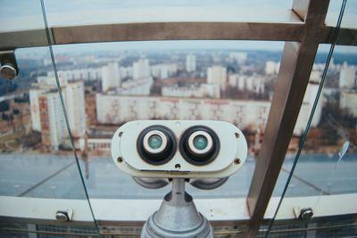 Close-up of coin-operated binoculars against cityscape