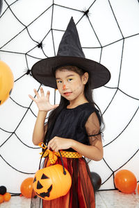 Low angle view of girl standing against orange wall during halloween
