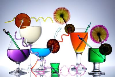 Various colorful drinks in glasses against white background