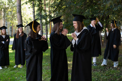 Rear view of woman wearing graduation gown standing in park