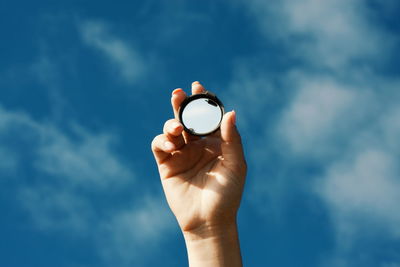 Low section of person holding hand against blue sky