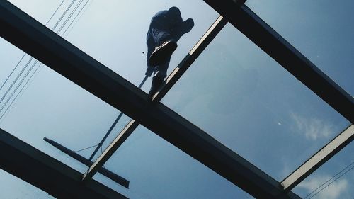 Low angle view of man working against clear sky