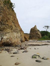 Rock formations on beach against sky