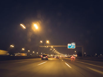 Cars on road against sky at night