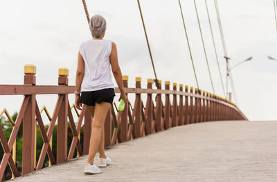 Woman exercise walking on the bridge with bottle water in her hand.