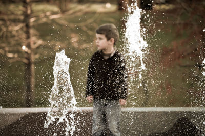 View of young boy through fountain