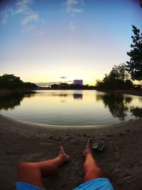Low section of woman relaxing on lake against sky
