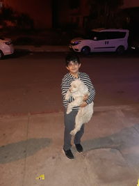 Full length of boy standing by car in city