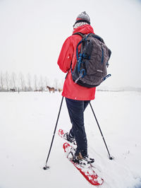 Woman snowshoeing in snow fall. dark grey clouds are full of fresh snow. winter sports