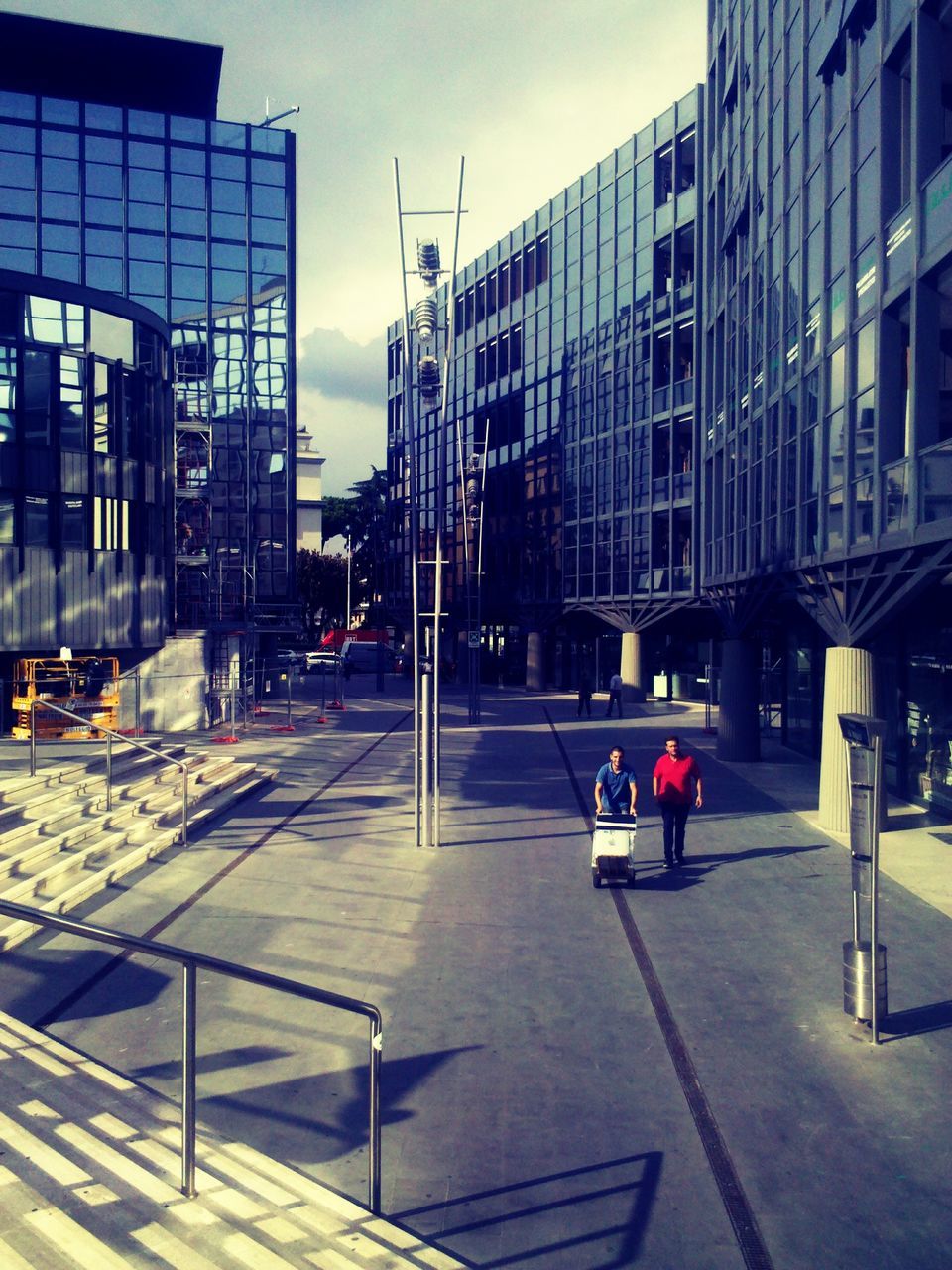 architecture, building exterior, built structure, city, building, transportation, sky, street, modern, office building, city life, incidental people, empty, the way forward, railing, day, road, sunlight, street light, outdoors