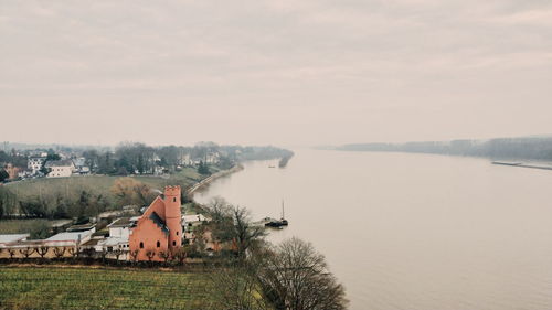 Houses by lake and buildings against sky