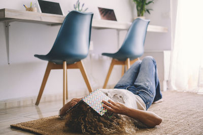 Rear view of woman sitting on floor at home