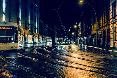 Illuminated street amidst buildings at night