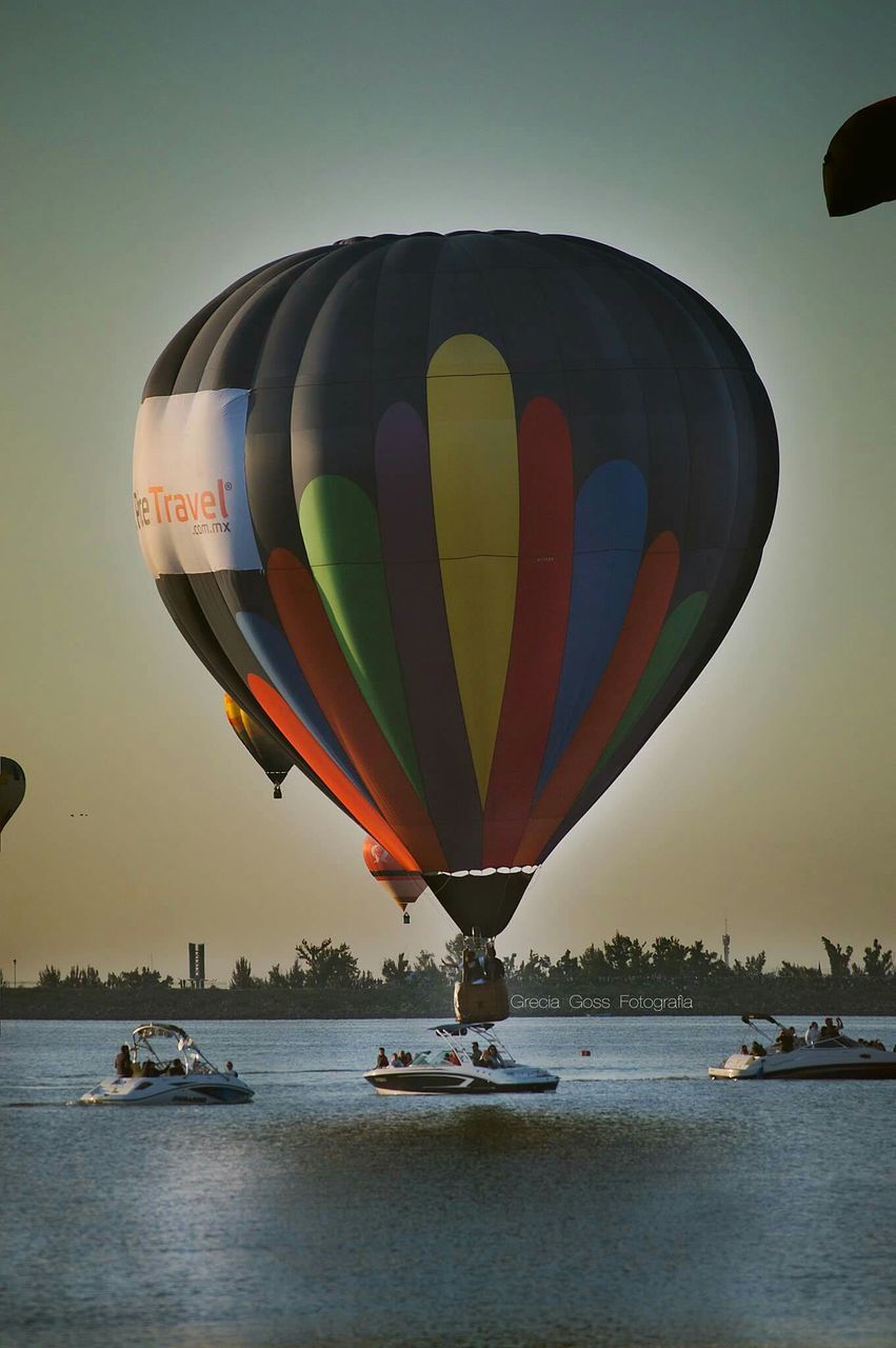 transportation, sea, mode of transport, nautical vessel, water, sky, boat, travel, waterfront, clear sky, tourism, multi colored, flying, beach, outdoors, travel destinations, hot air balloon, incidental people, tranquility, vacations