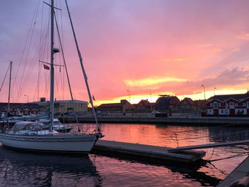 Boats moored at harbor during sunset