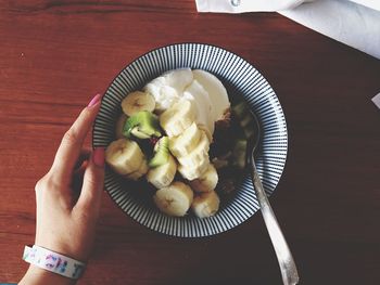 Woman relishing fruit and granola with ice cream in bowl