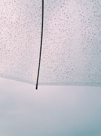 Low angle view of raindrops on windshield against sky