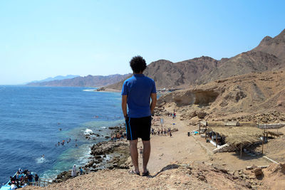 Rear view of man looking at sea while standing on mountain