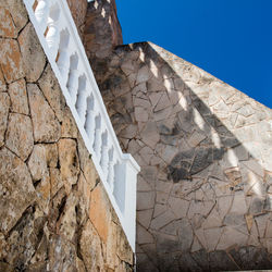 Low angle view of stone wall against clear blue sky