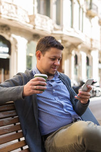 Man using smart phone sitting on bench